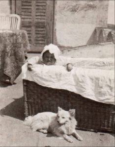 Die Spitzin Pipsi liegt wachsam und schützend vor einem Kleinkind (Foto von 1923)